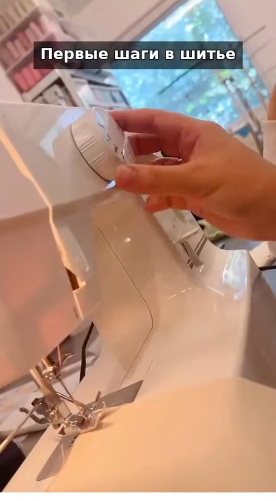 A still from our class video: a hand setting the dial on a sewing machine in the studio.