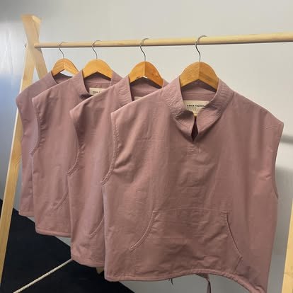 A production run of identical mauve sleeveless tops for Xenia Telunts on a rail in the studio.