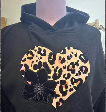A black hoodie decorated with a leopard-print heart and black lace flower appliqué.