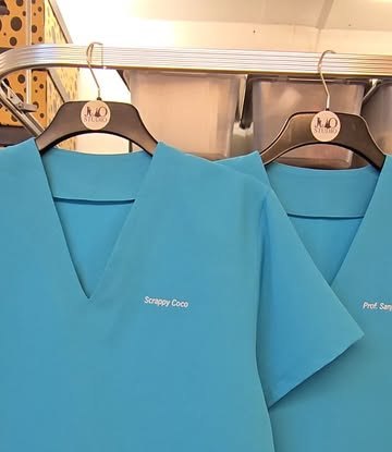 Turquoise clinical tunics on hangers with names embroidered on the chest.
