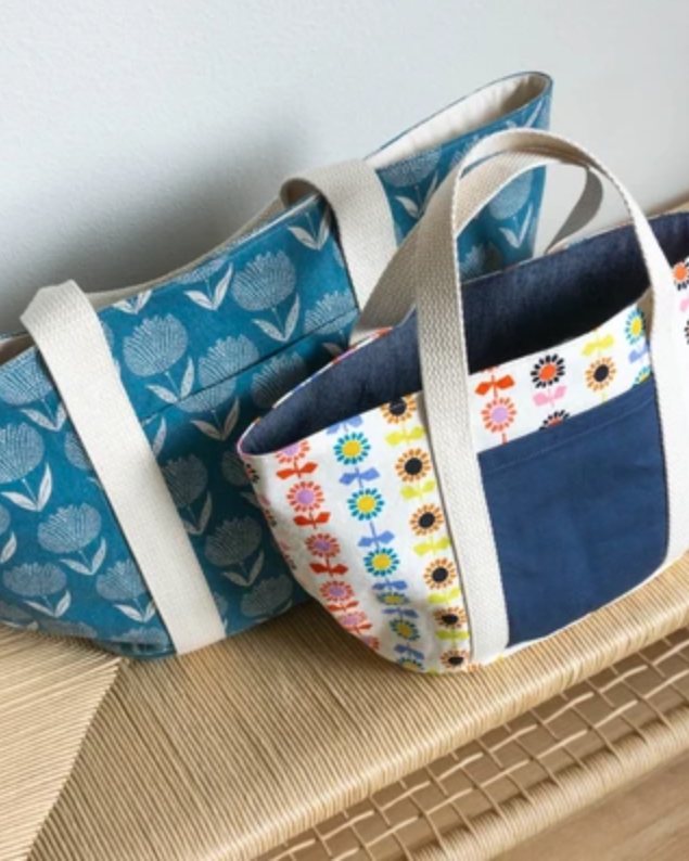 Two fabric tote bags with cotton webbing handles, one in teal print and one in a floral print.