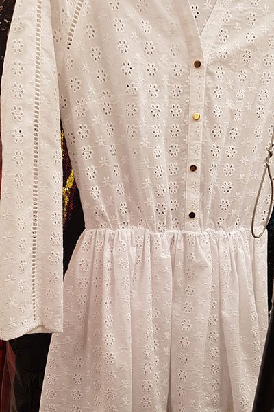A white broderie dress with a buttoned placket and gathered skirt.