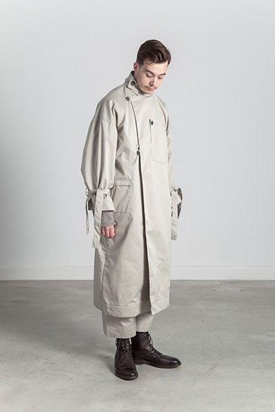 A model in an oversized stone cotton trench coat with tied sleeves.